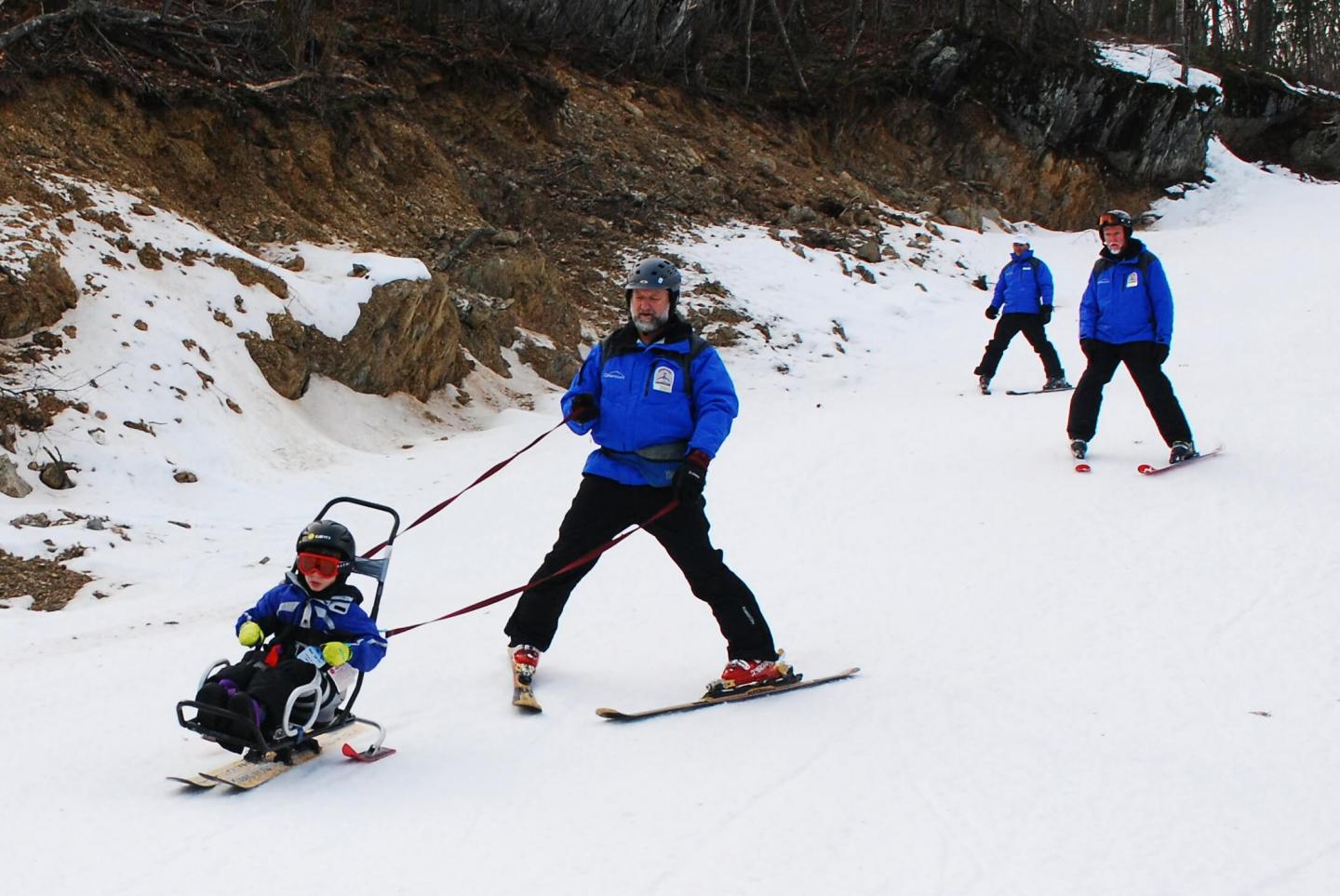 Ski Instructors using a ski chair and leash in the Stride Adaptive Program